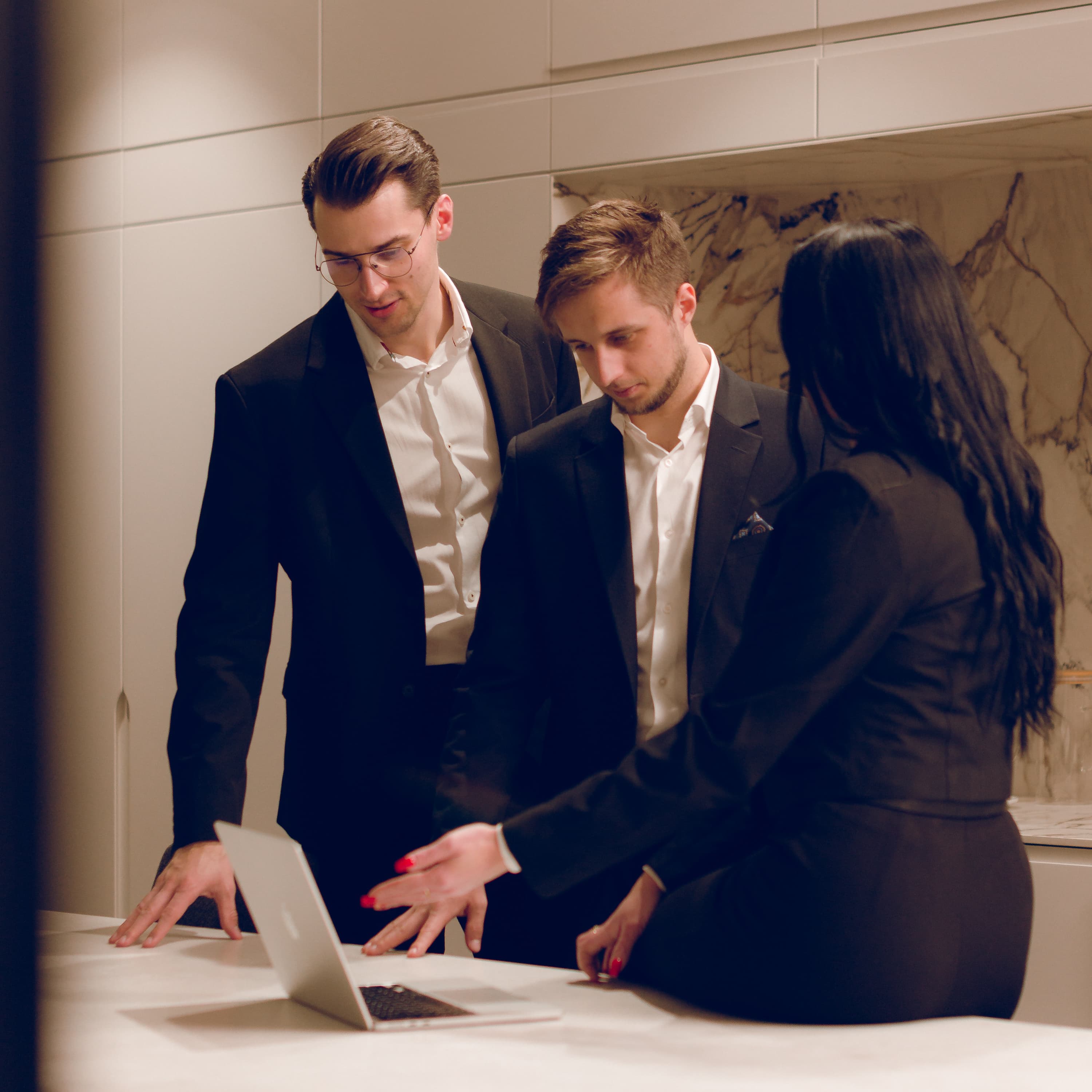 A woman presents materials from a folder to two men in the office.